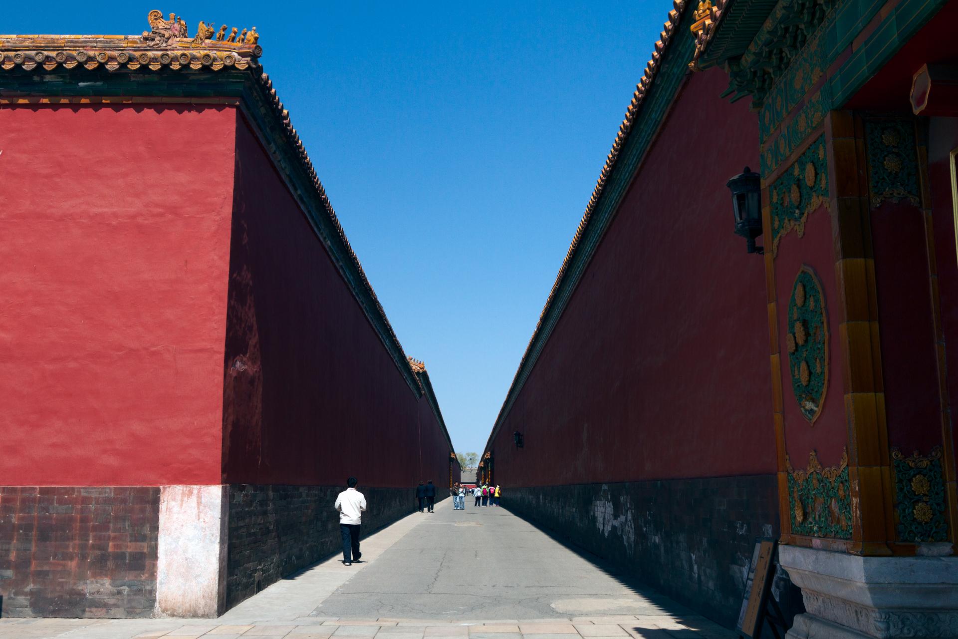 A deep lane between towering red walls inside the Forbidden City