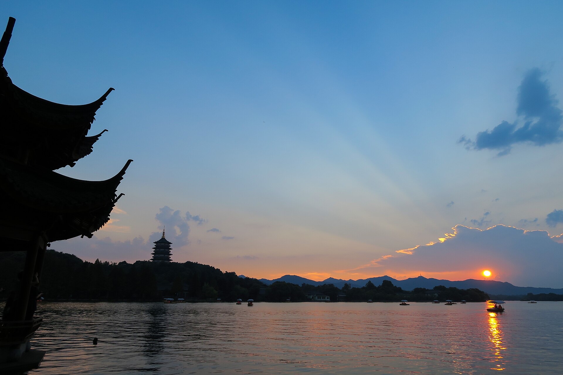 Sunset over West Lake with a lakeside pavilion silhouette, the Leifeng Pagoda and small boats on the water