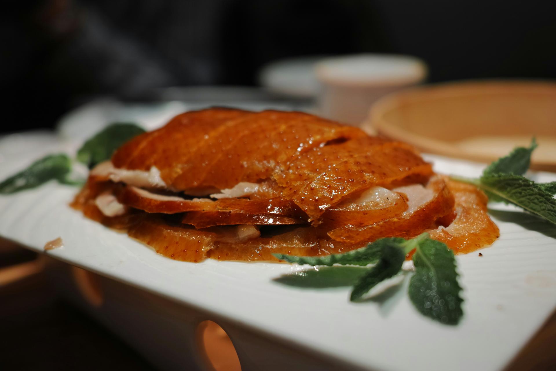 Sliced Beijing roast duck, lacquered skin, plated with mint leaves