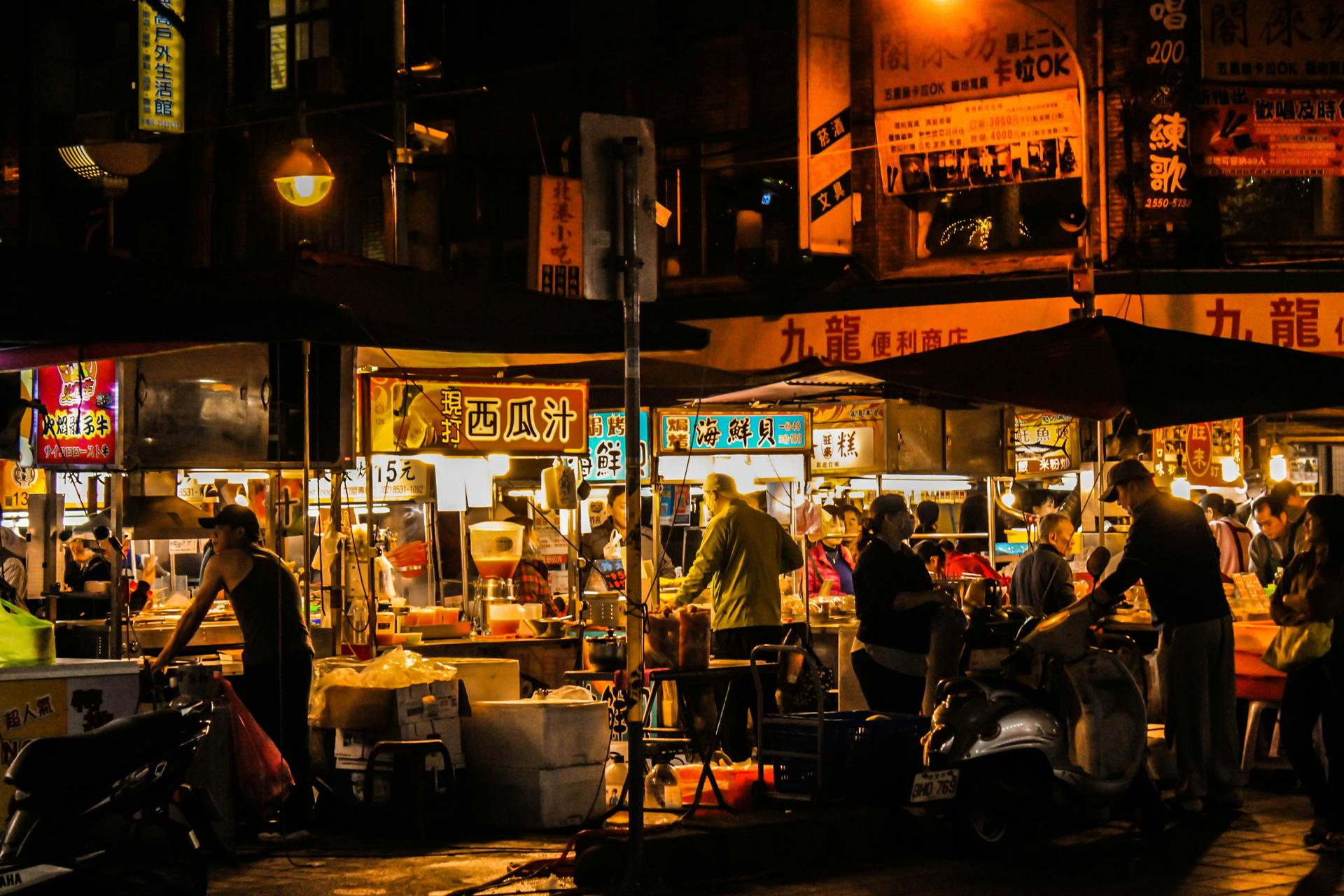 A night market street-food stall steaming under neon signs