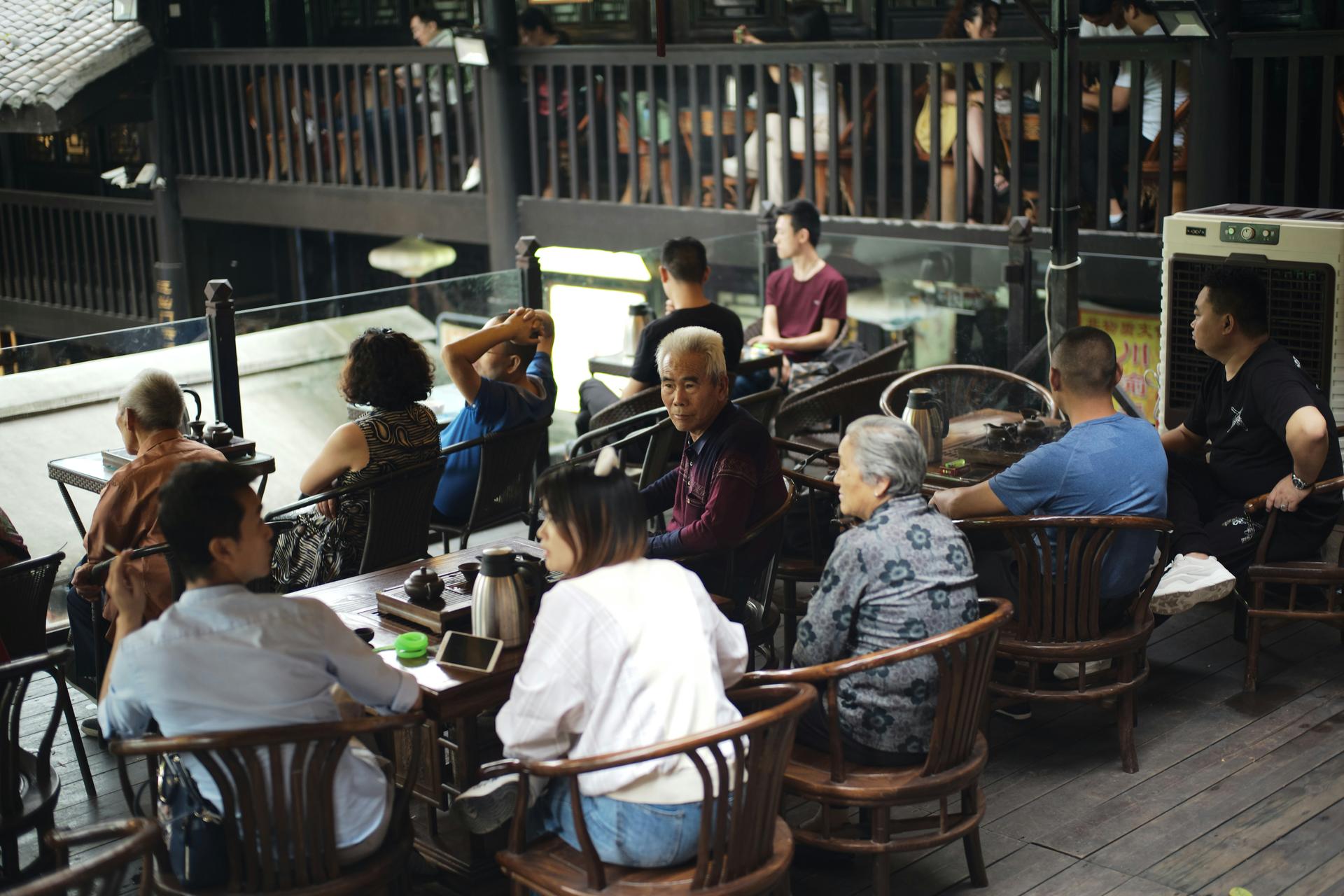 Regulars at a Chinese tea house, teapots and thermos flasks on the tables