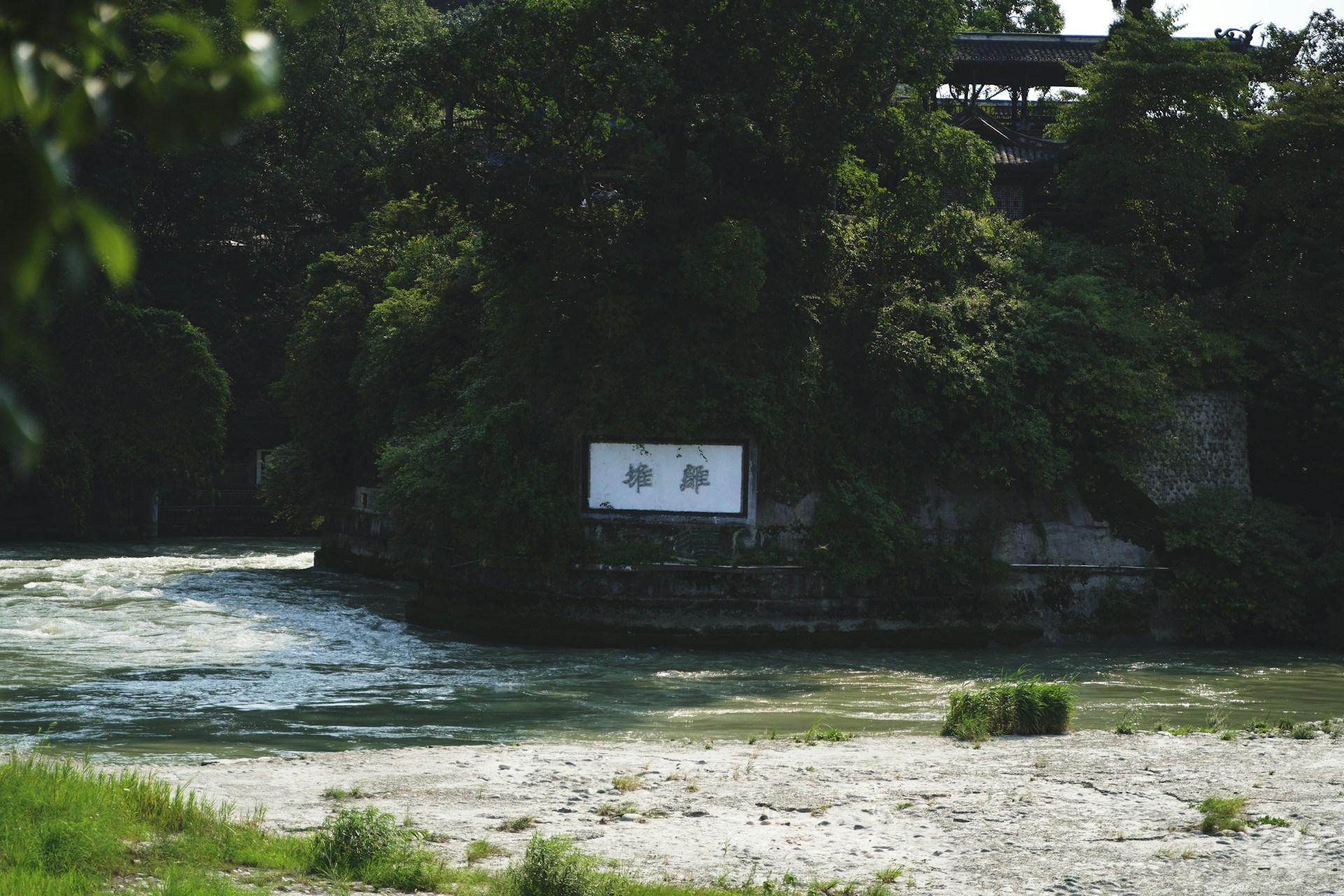 The Minjiang rushing past the wooded Lidui mound at Dujiangyan, below the temple