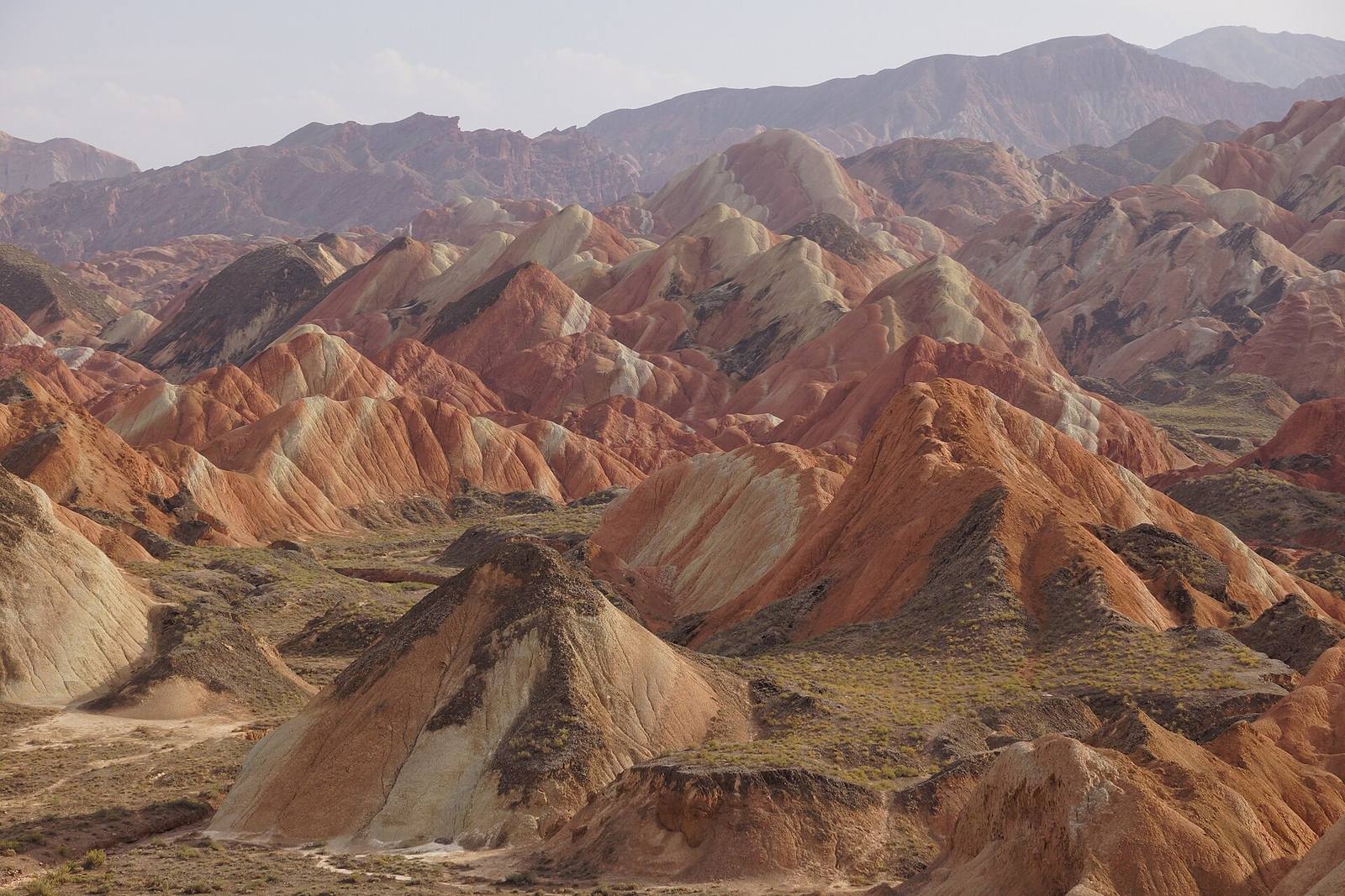 Geschichtete Grate aus rotem, ocker- und cremefarbenem Fels in der Danxia-Landschaft von Zhangye