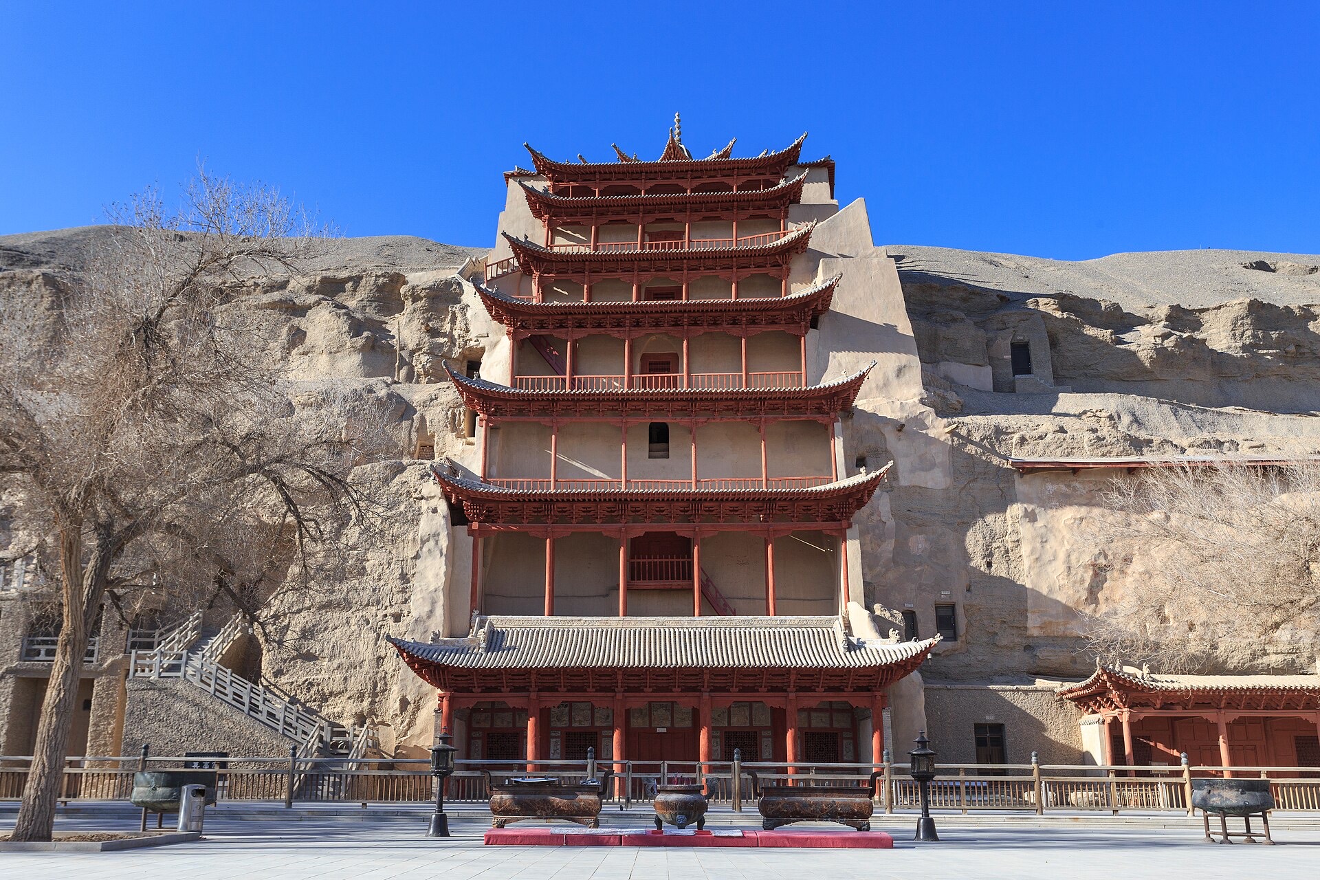 The nine-storey pagoda of the Mogao Caves set into the dun-coloured cliff, Dunhuang