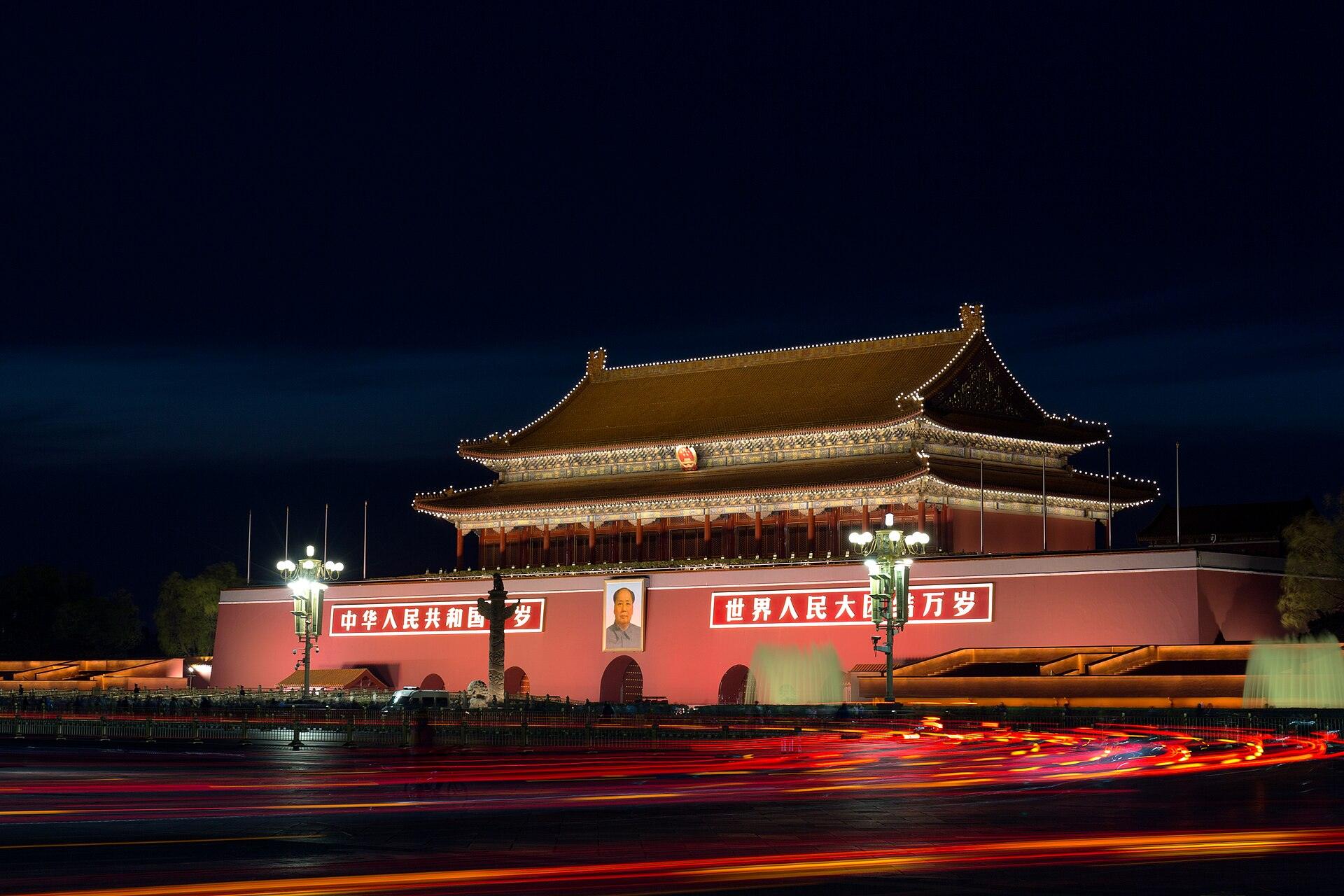 Tiananmen Gate illuminated at night with traffic light trails on Chang'an Avenue
