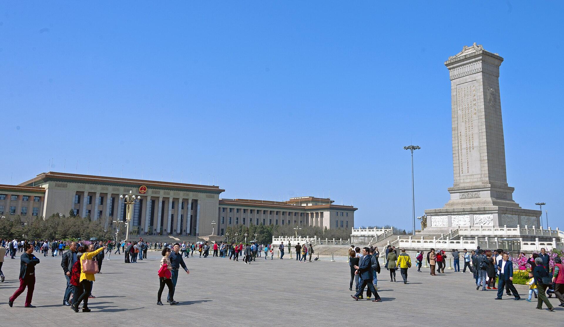 Visitors crossing the open expanse of Tiananmen Square with the Monument and the Great Hall beyond